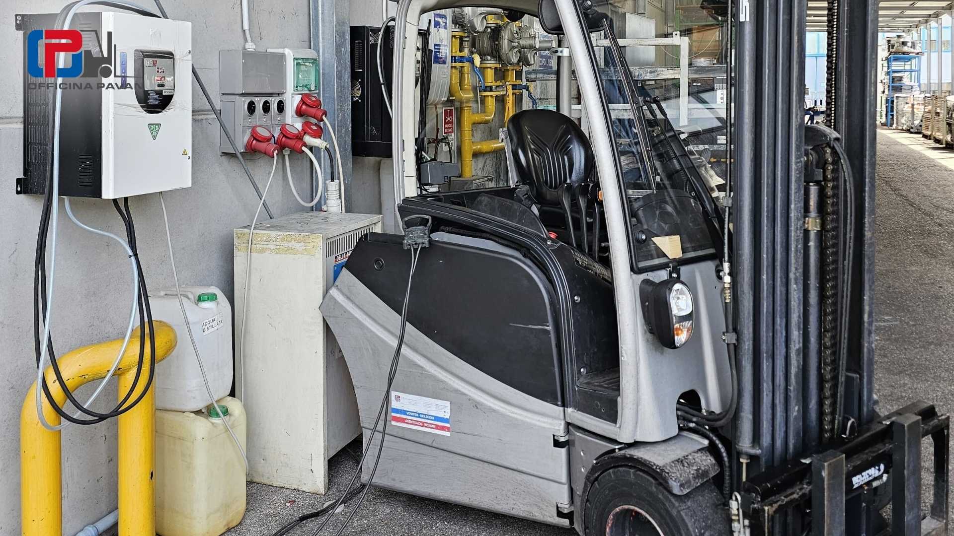 Carrello elevatore elettrico in fase di ricarica presso una stazione di ricarica industriale